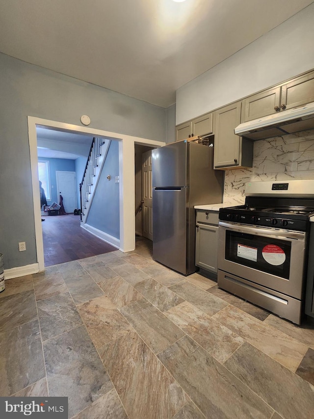 kitchen with gray cabinetry, backsplash, appliances with stainless steel finishes, and light wood-type flooring