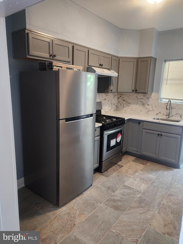 kitchen featuring backsplash, stainless steel refrigerator, light tile patterned floors, sink, and range with gas cooktop