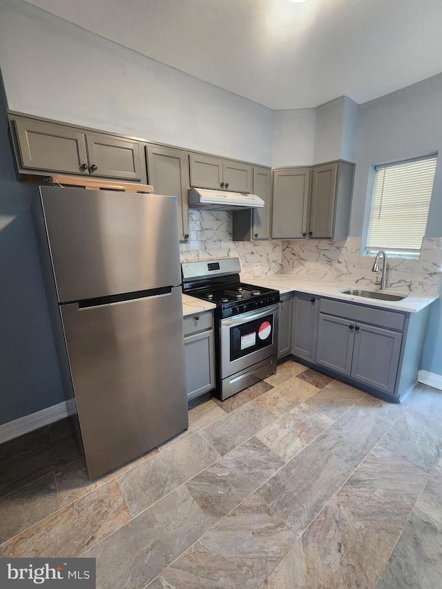 kitchen with appliances with stainless steel finishes, decorative backsplash, sink, gray cabinetry, and light tile patterned floors