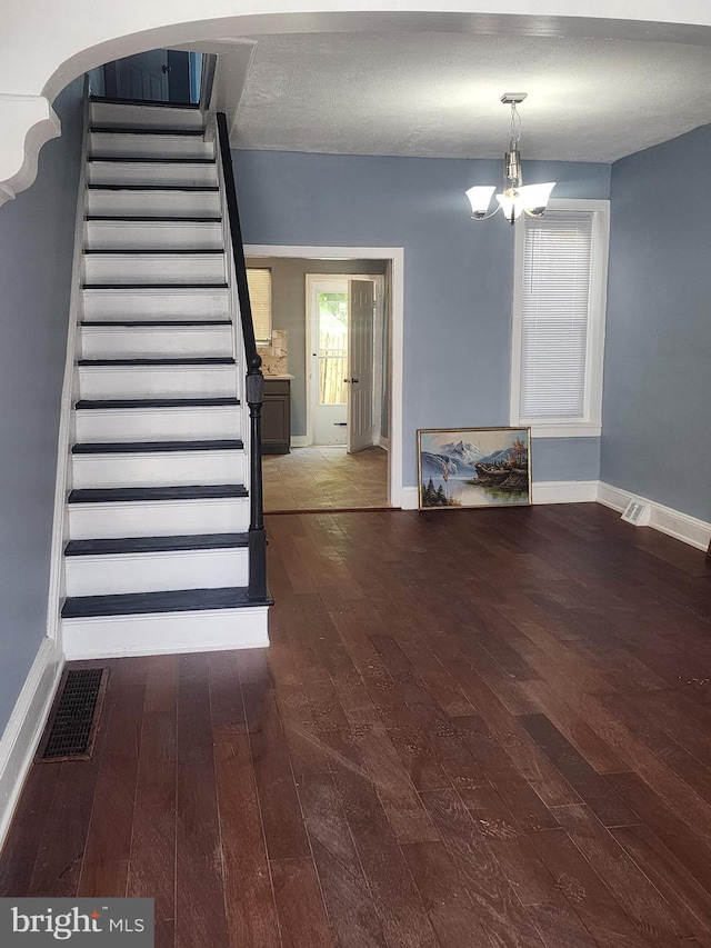 interior space with stairs, baseboards, wood finished floors, and an inviting chandelier