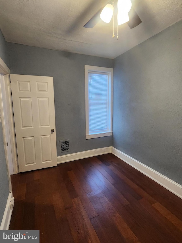 empty room with dark hardwood / wood-style flooring, a textured ceiling, and ceiling fan