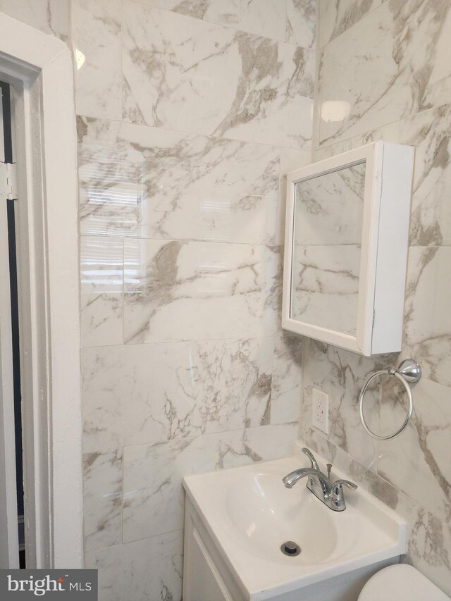 bathroom with tile walls, toilet, and vanity