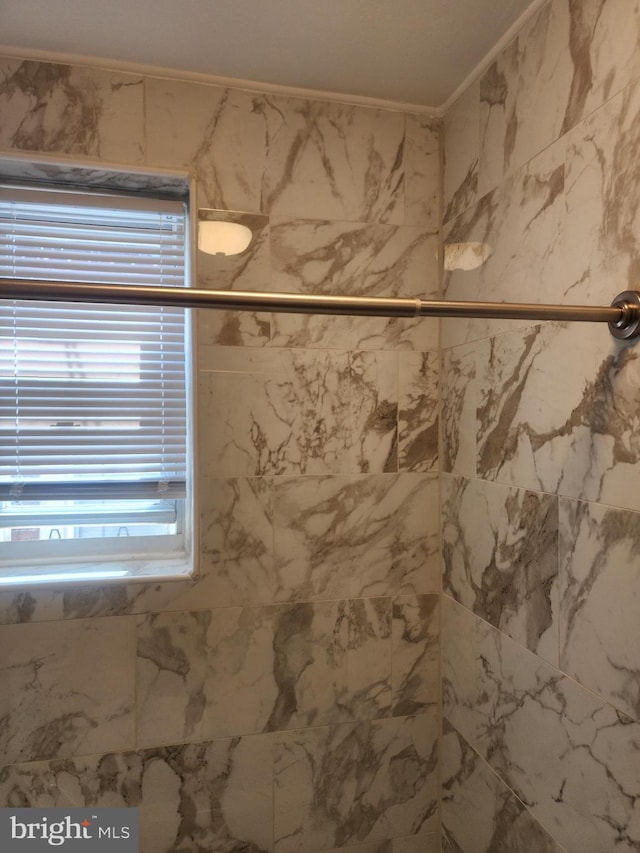 bathroom with tiled shower and ornamental molding