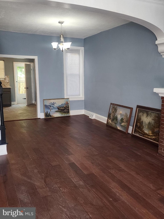 unfurnished living room featuring hardwood / wood-style flooring and an inviting chandelier