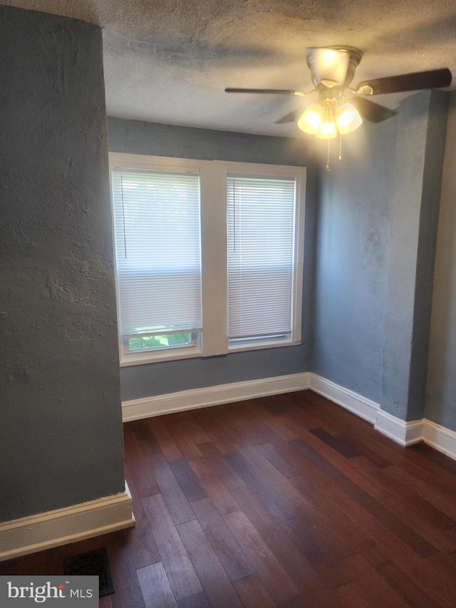 spare room with a textured ceiling, ceiling fan, and dark hardwood / wood-style floors