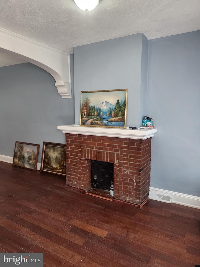 living room featuring a textured ceiling, a brick fireplace, and hardwood / wood-style floors