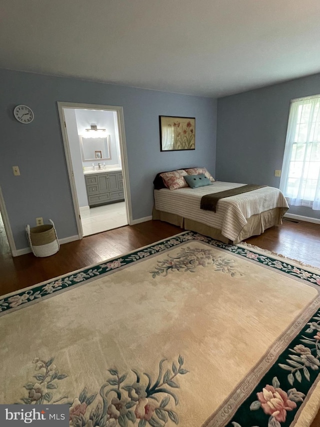 bedroom with connected bathroom and hardwood / wood-style floors