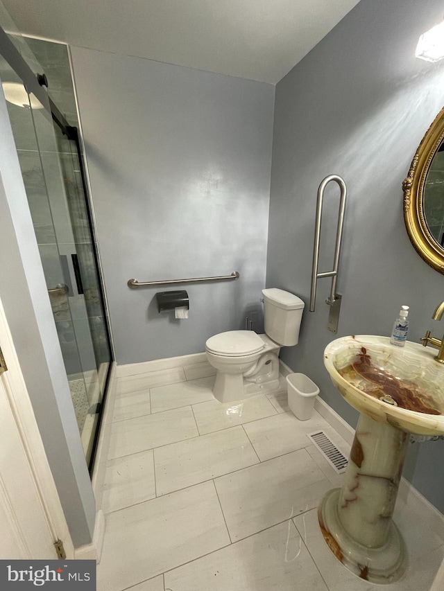 bathroom featuring tile patterned flooring, walk in shower, and toilet