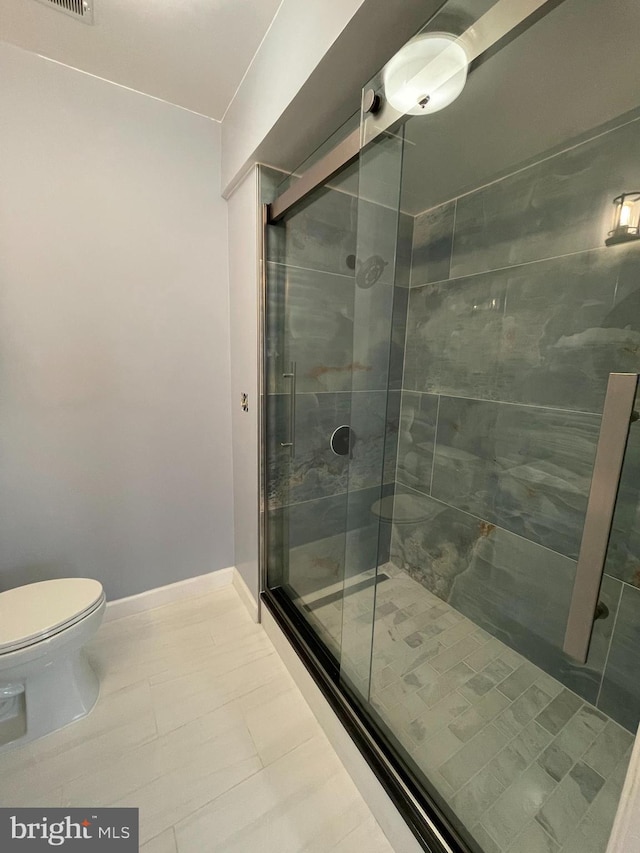 bathroom featuring tile patterned flooring, an enclosed shower, and toilet