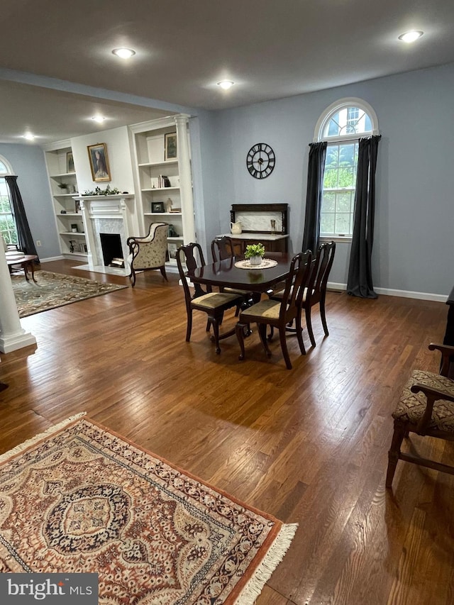 dining area featuring ornate columns, hardwood / wood-style flooring, and built in features