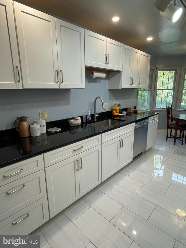 kitchen featuring light tile patterned floors, stainless steel dishwasher, sink, and white cabinets