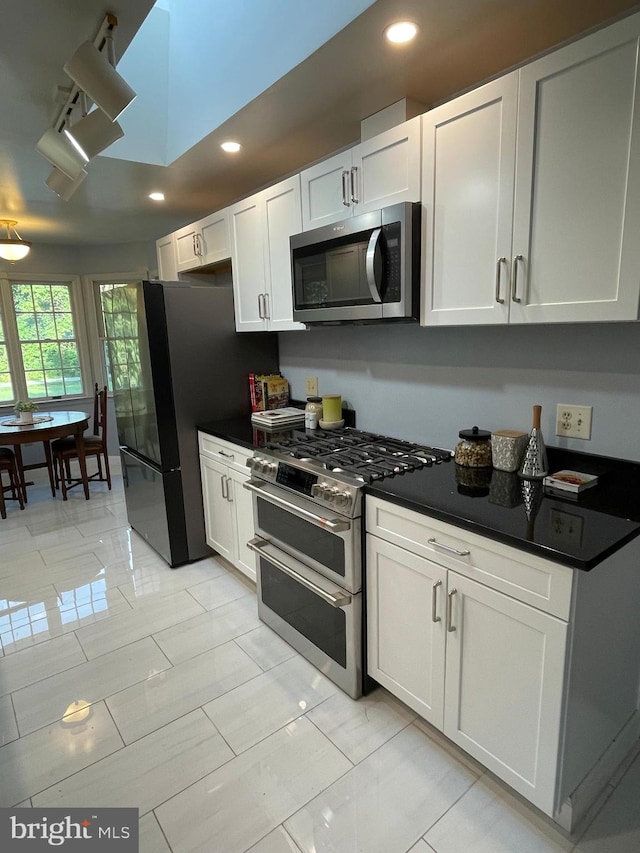 kitchen with white cabinets, rail lighting, light tile patterned flooring, and stainless steel appliances