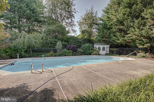 view of pool featuring an outbuilding, a storage unit, fence, and a fenced in pool