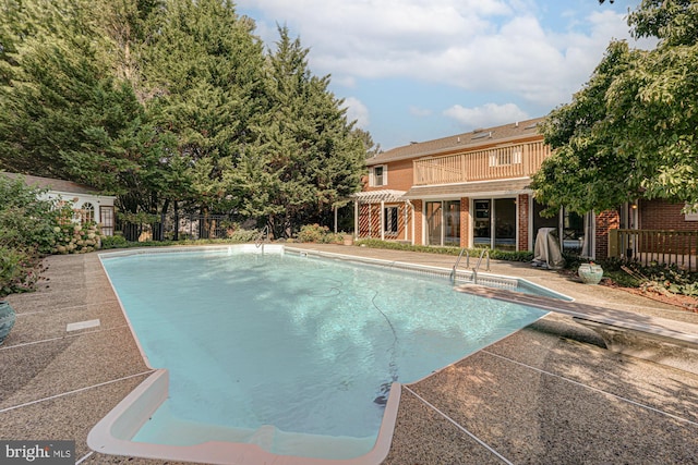 view of swimming pool featuring fence, a diving board, a fenced in pool, a pergola, and a patio area