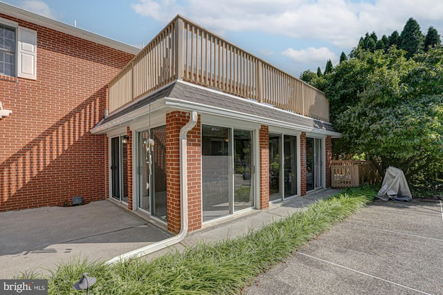 rear view of house with brick siding and a balcony