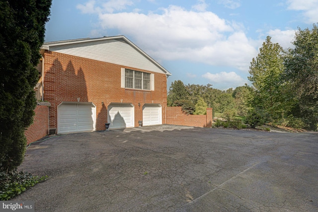 view of home's exterior featuring an attached garage, aphalt driveway, and brick siding