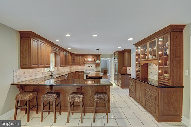 kitchen with a breakfast bar area, stainless steel stove, a peninsula, tasteful backsplash, and glass insert cabinets