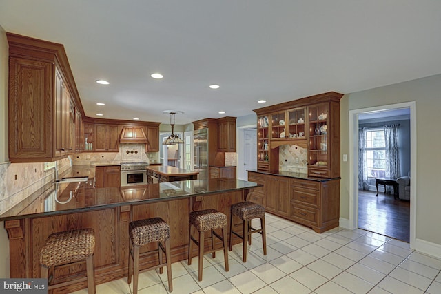 kitchen featuring a peninsula, backsplash, high quality appliances, and custom range hood