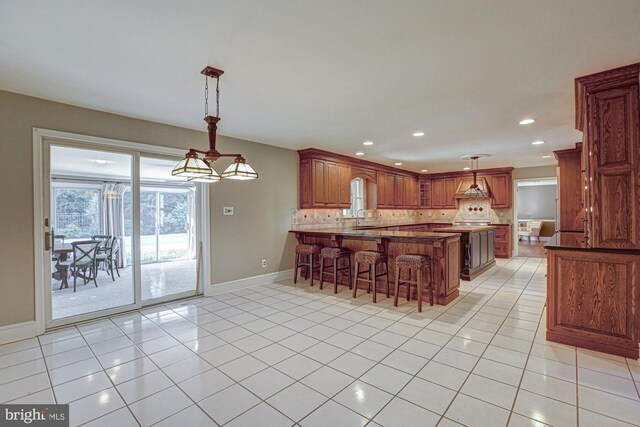 kitchen featuring tasteful backsplash, a sink, a peninsula, and light tile patterned floors