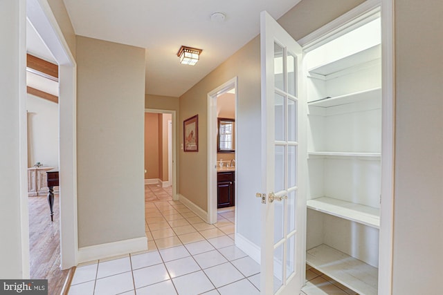 corridor featuring baseboards and light tile patterned flooring