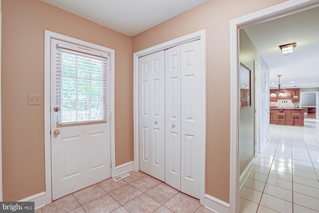 doorway with visible vents, baseboards, and light tile patterned floors