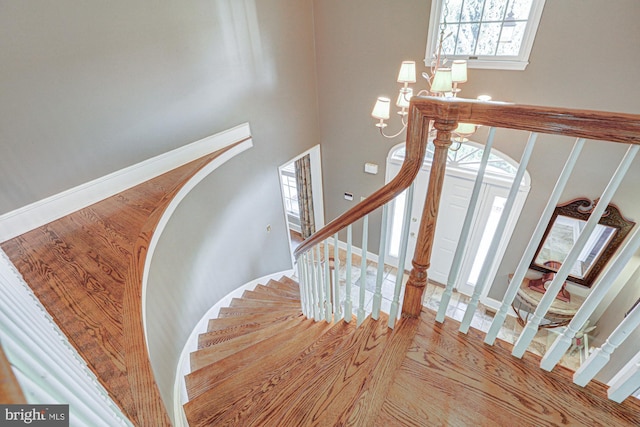 stairs with baseboards, arched walkways, and wood finished floors