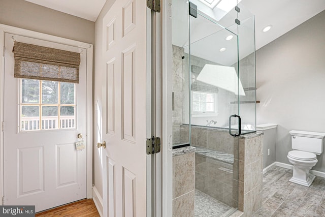 bathroom with toilet, recessed lighting, wood finished floors, baseboards, and a shower stall