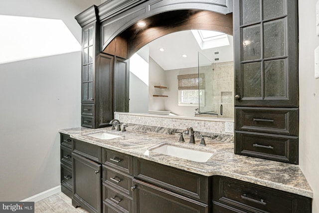 full bathroom with double vanity, a stall shower, a sink, and baseboards