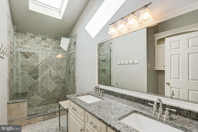 bathroom featuring double vanity, a stall shower, vaulted ceiling with skylight, and a sink