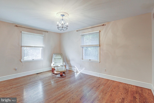 unfurnished room with plenty of natural light, wood finished floors, and visible vents