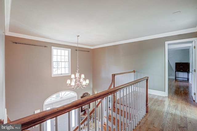 hall with ornamental molding, an upstairs landing, wood finished floors, a chandelier, and baseboards