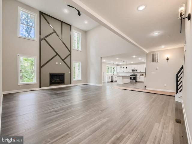 unfurnished living room featuring plenty of natural light, visible vents, a fireplace, and wood finished floors