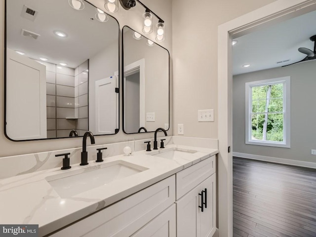 full bath featuring double vanity, visible vents, a sink, and wood finished floors