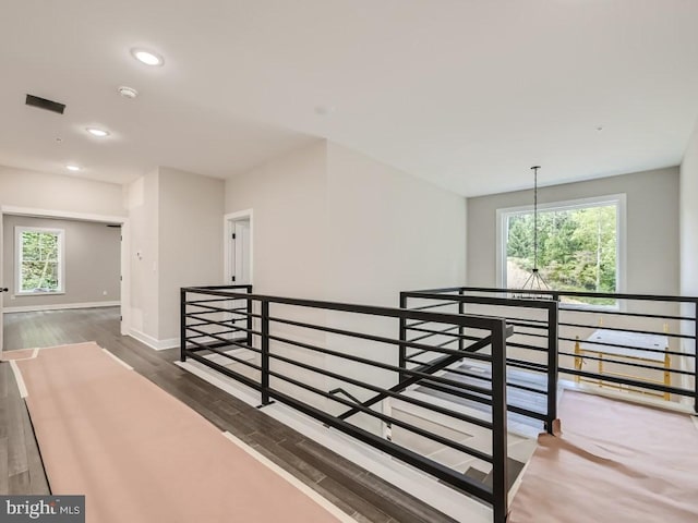 hallway with dark wood-type flooring, recessed lighting, a healthy amount of sunlight, and an upstairs landing