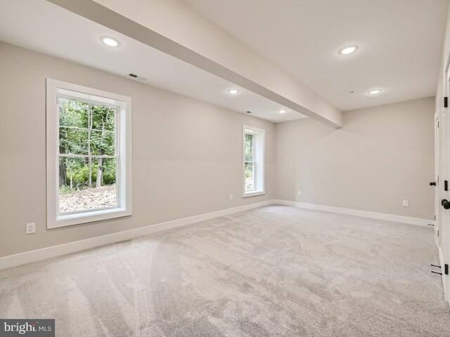 spare room featuring beamed ceiling and light carpet