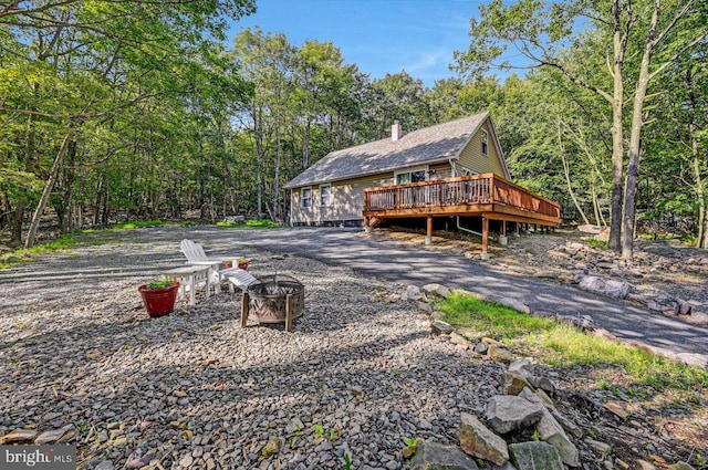 rear view of property featuring an outdoor fire pit and a wooden deck