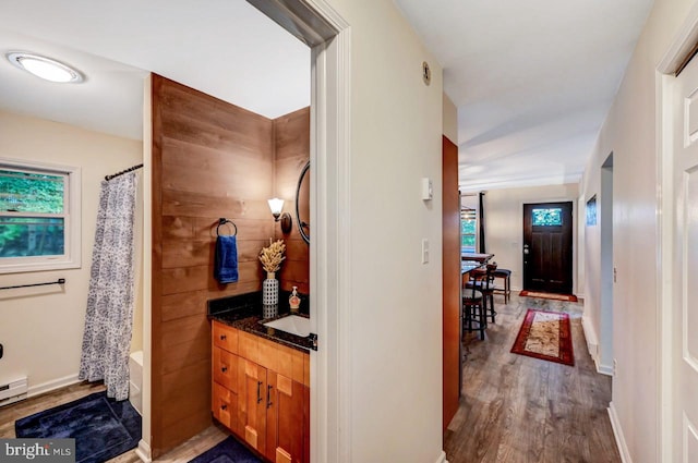 corridor with hardwood / wood-style floors, a baseboard heating unit, and sink