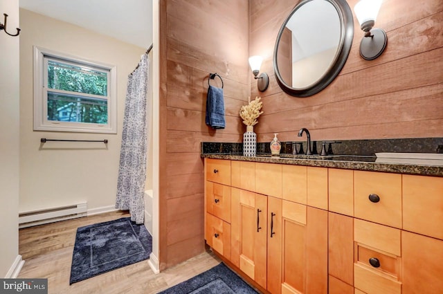 bathroom with vanity, shower / tub combo with curtain, wooden walls, wood-type flooring, and a baseboard radiator