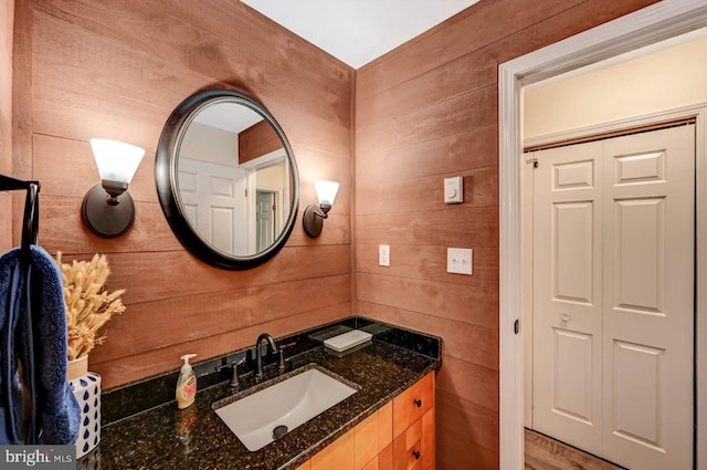 bathroom with hardwood / wood-style floors, vanity, and wooden walls