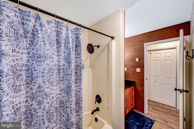 bathroom with shower / bath combination with curtain, hardwood / wood-style flooring, and wood walls