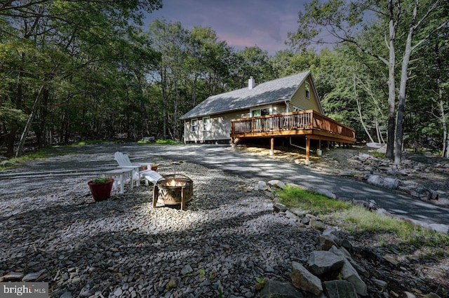 back house at dusk with a fire pit and a wooden deck