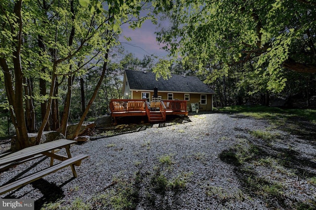 back house at dusk featuring a deck