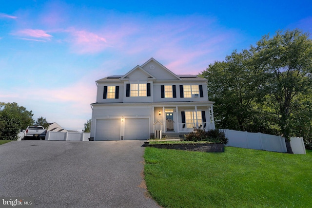 view of front of property with a garage, covered porch, and a lawn