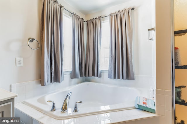 bathroom featuring tiled bath and vanity