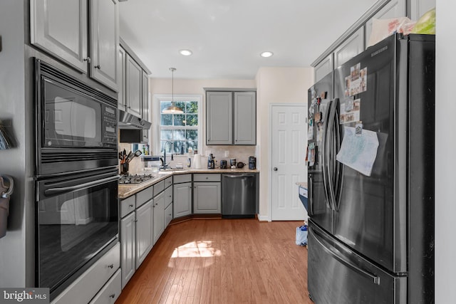 kitchen with light hardwood / wood-style floors, sink, black appliances, pendant lighting, and gray cabinets