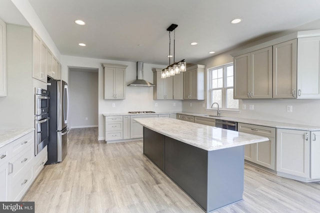 kitchen with sink, gray cabinetry, a kitchen island, appliances with stainless steel finishes, and wall chimney range hood