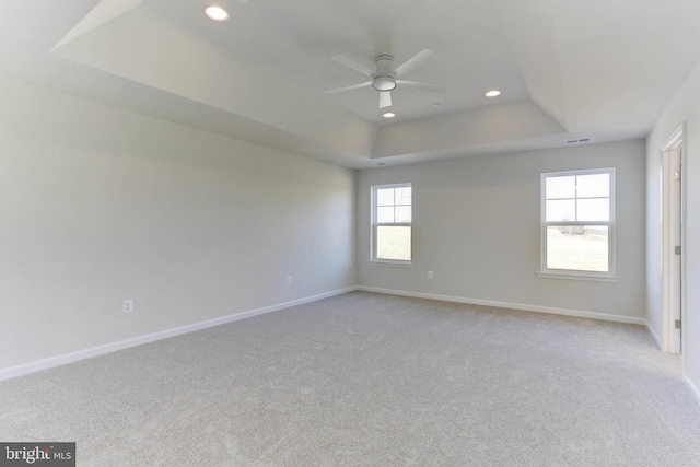 carpeted empty room featuring a raised ceiling and ceiling fan