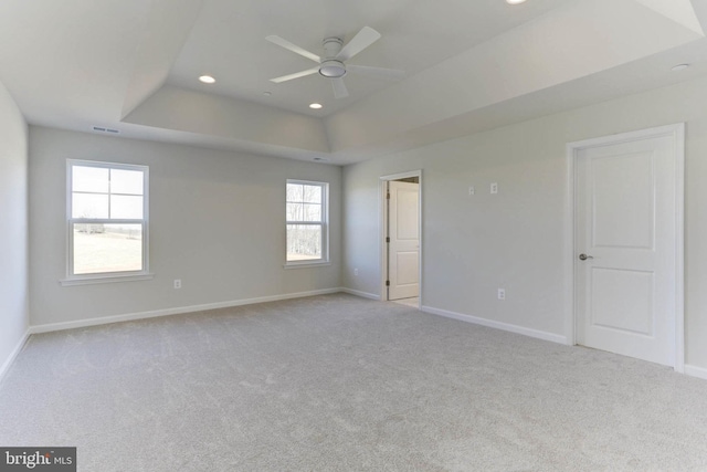 empty room featuring light colored carpet, a raised ceiling, and ceiling fan