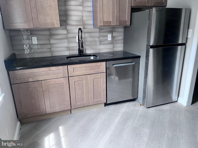 kitchen with light hardwood / wood-style floors, stainless steel appliances, sink, and decorative backsplash