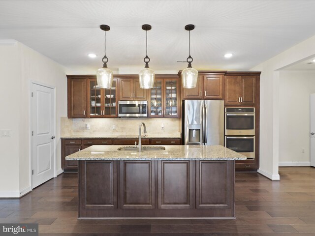 kitchen with stainless steel appliances, dark hardwood / wood-style floors, tasteful backsplash, light stone countertops, and washer and dryer